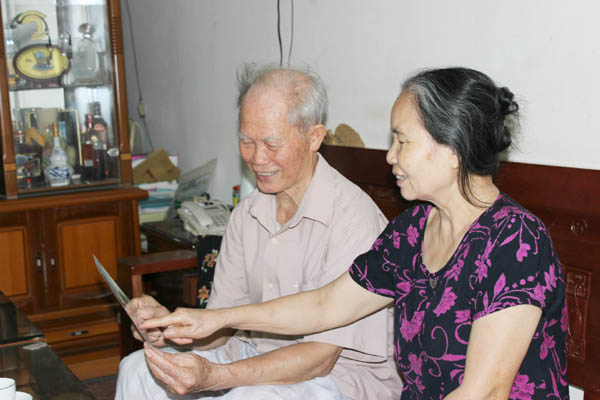 Cựu chiến binh Nguyễn Xuân Lợi cùng vợ xem lại những bức ảnh về kỷ niệm 2 lần vinh dự được đón Bác.