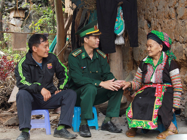 Trung tá Nguyễn Đình Dy (người ngồi giữa) thăm hỏi, vận động bà con phát triển kinh tế.