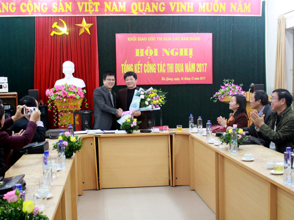 Đồng chí Nguyễn Trung Thu, Tỉnh ủy viên, Tổng Biên tập Báo Hà Giang trao Sổ giao ước thi đua và tặng hoa cho lãnh đạo Văn phòng Tỉnh ủy – đơn vị được bầu làm Trưởng khối giao ước thi đua năm 2018.