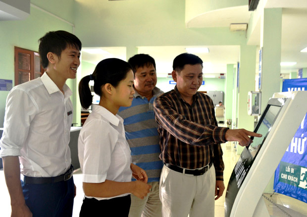 Các cán bộ Trung tâm phục vụ Hành chính công - Văn phòng UBND tỉnh hướng dẫn, tư vấn cho khách hàng (ngoài cùng bên phải) thực hiện giao dịch hành chính.