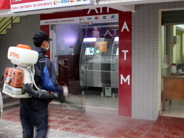 Nhân viên Trung tâm Y tế dự phòng thành phố phun thuốc tiêu độc, khử trùng khu vực cây ATM và bên trong quầy giao dịch Yên Biên.
