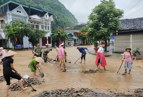 Các lực lượng phối hợp dọn dẹp bùn đất, khơi thông dòng chảy trên các trục đường ở thị trấn Mèo Vạc. Ảnh: KIM TIẾN