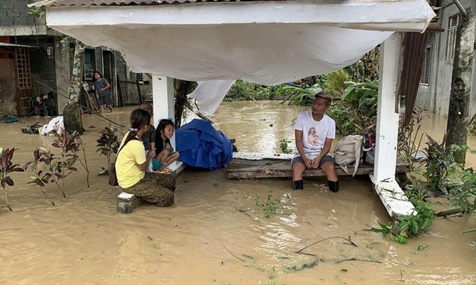 Người dân ngồi cạnh ngôi nhà bị ngập nước do bão Molave ở tỉnh Oriental Mindoro, Philippines, hôm 26/10. Ảnh: AFP.