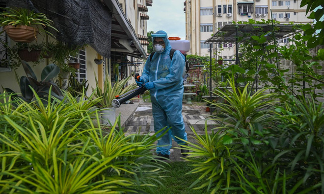 Nhân viên y tế phun thuốc khử trùng tại sân một tòa nhà chung cư ở thành phố Kuala Lumpur, Malaysia. Ảnh: Getty Images