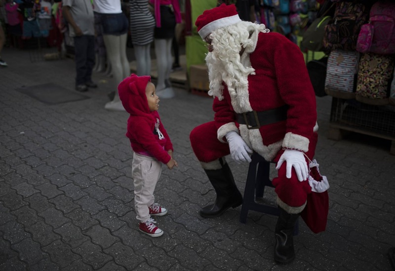 Cô bé trò chuyện với ông già Noel tại hội chợ Giáng sinh diễn ra ở thủ đô Caracas, Venezuela. (Ảnh: AP)
