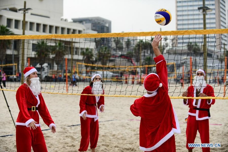 Người dân tại TP Tel Aviv, Israel chơi bóng chuyền trong trang phục của ông già tuyết. (Ảnh: Tân Hoa xã)