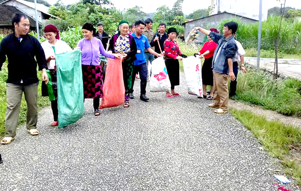 Anh Vàng Minh Thề (ở giữa đeo thẻ) cùng người dân dọn dẹp, vệ sinh môi trường khu vực trung tâm xã.                                      
