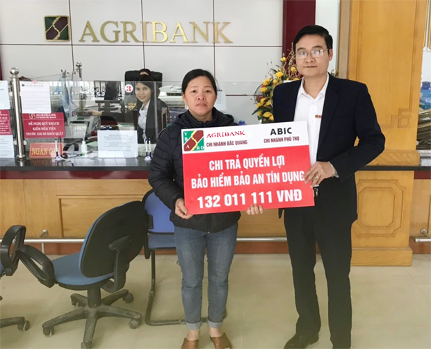 Ông Phạm Đức Quang, Giám đốc phòng Giao dịch Gia Tự - Agribank Chi nhánh Bắc Quang trao tiền chi trả quyền lợi Bảo an tín dụng cho gia đình ông Hoàng Văn Thanh.