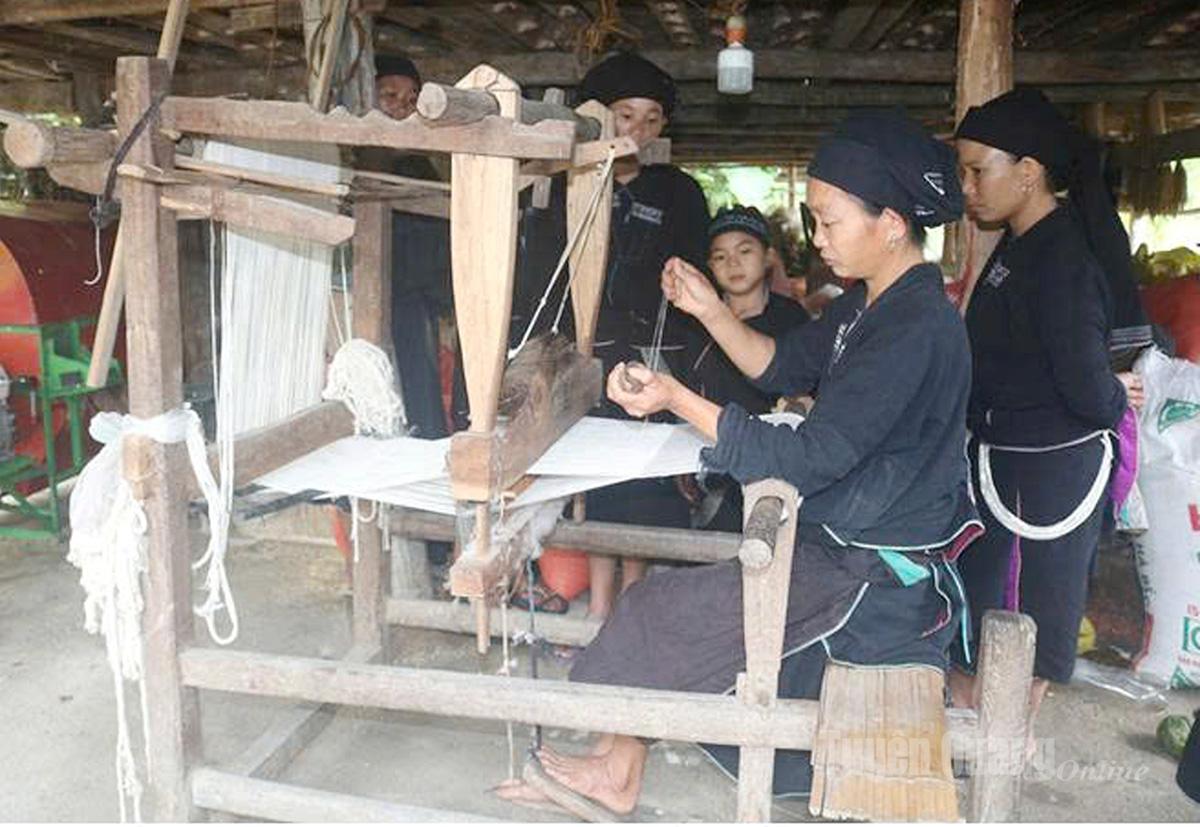 Nghệ nhân La Chí hướng dẫn thế hệ trẻ mắc khung luồn chỉ, truyền dạy nghề dệt theo hình thức cầm tay chỉ việc.