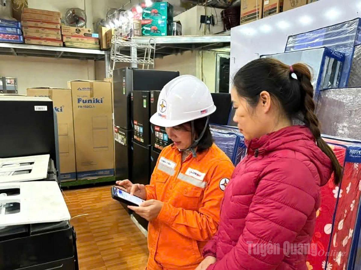 Công nhân Công ty Điện lực Tuyên Quang hướng dẫn người dân kiểm tra sản lượng điện tiêu thụ của gia đình trên điện thoại thông minh.
