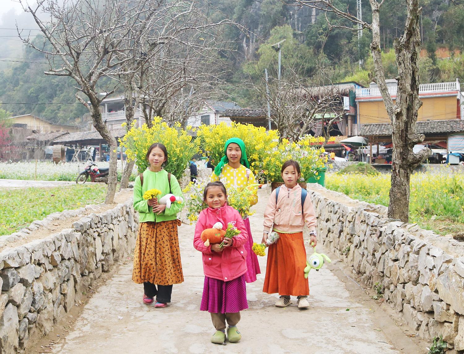 Friendly children with baskets brimming with mustard flowers.