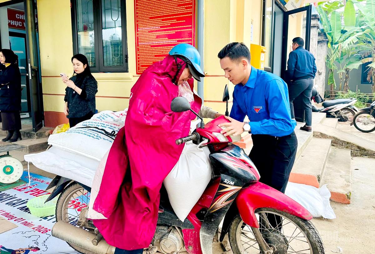 Cán bộ đoàn viên thanh niên xã Tân Trịnh hỗ trợ người dân vận chuyển gạo tại điểm cấp phát.