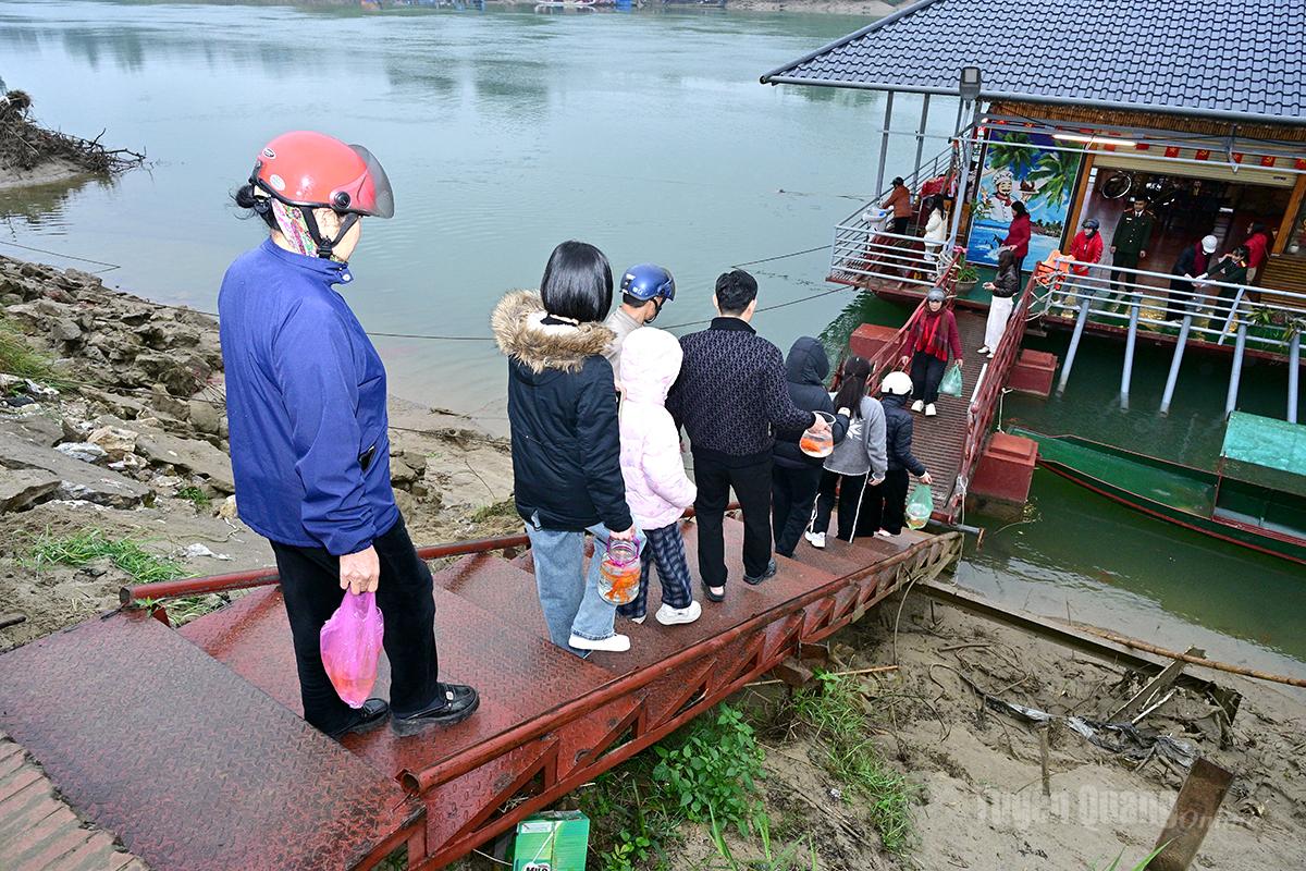 The area around the Song Lo Ferry Terminal in Minh Xuan Ward is crowded with residents releasing carp in a ritual act of merit-making.
