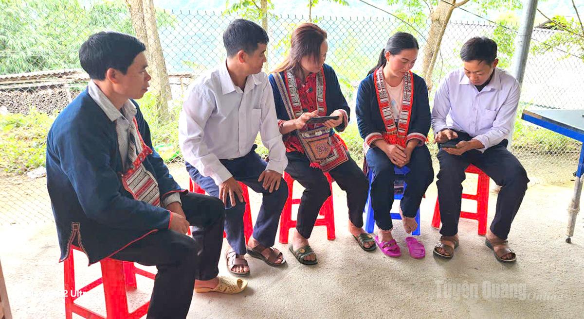 Bí thư Chi bộ thôn Tân Thành Triệu Tà Khao (bên phải) hướng dẫn đảng viên sử dụng điện thoại để cập nhật văn bản của chi bộ.