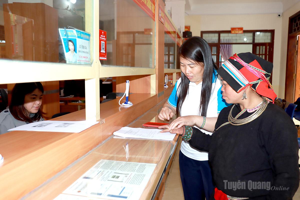 Cán bộ xã Quản Bạ hướng dẫn người dân điểm chỉ vào các văn bản giấy tờ thay chữ ký.