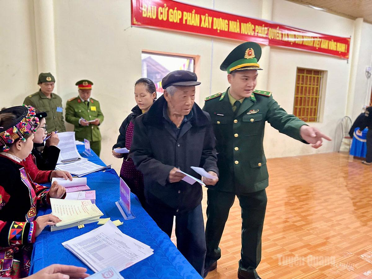 Cán bộ Đồn Biên phòng Lũng Cú hỗ trợ cử tri cao tuổi tại khu vực bỏ phiếu số 5, xã Lũng Cú. Ảnh: Thảo Nguyên