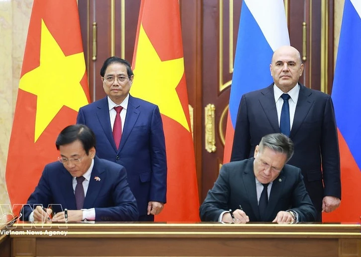 Vietnamese PM Pham Minh Chinh (standing, left) and his Russian counterpart Mikhail Mishustin (standing, right) witness the signing of the agreement between the two governments on cooperation in building a nuclear power plant on the territory of Viet Nam. (Photo: VNA)
