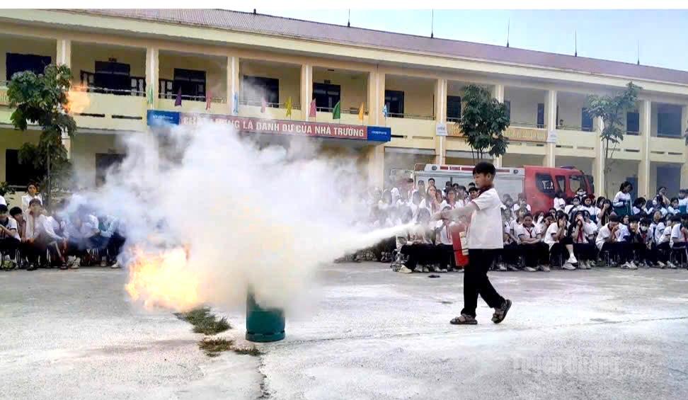 Học sinh, giáo viên và phụ huynh trường THCS Trung Môn thực hành sử dụng bình chữa cháy xách tay dập tắt đám cháy giả định.