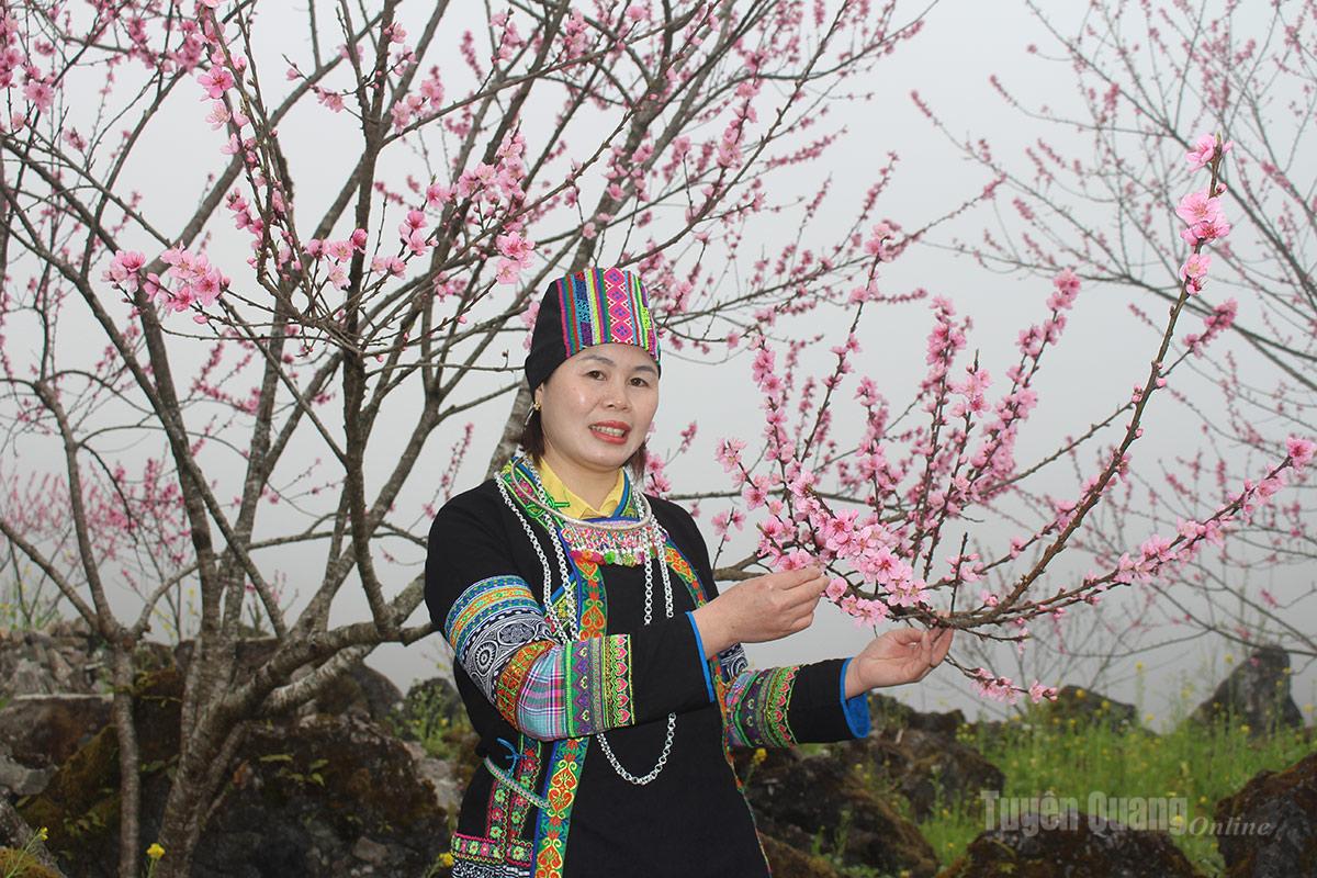 Visitors pose beside the vibrant peach blossoms, capturing memorable moments.