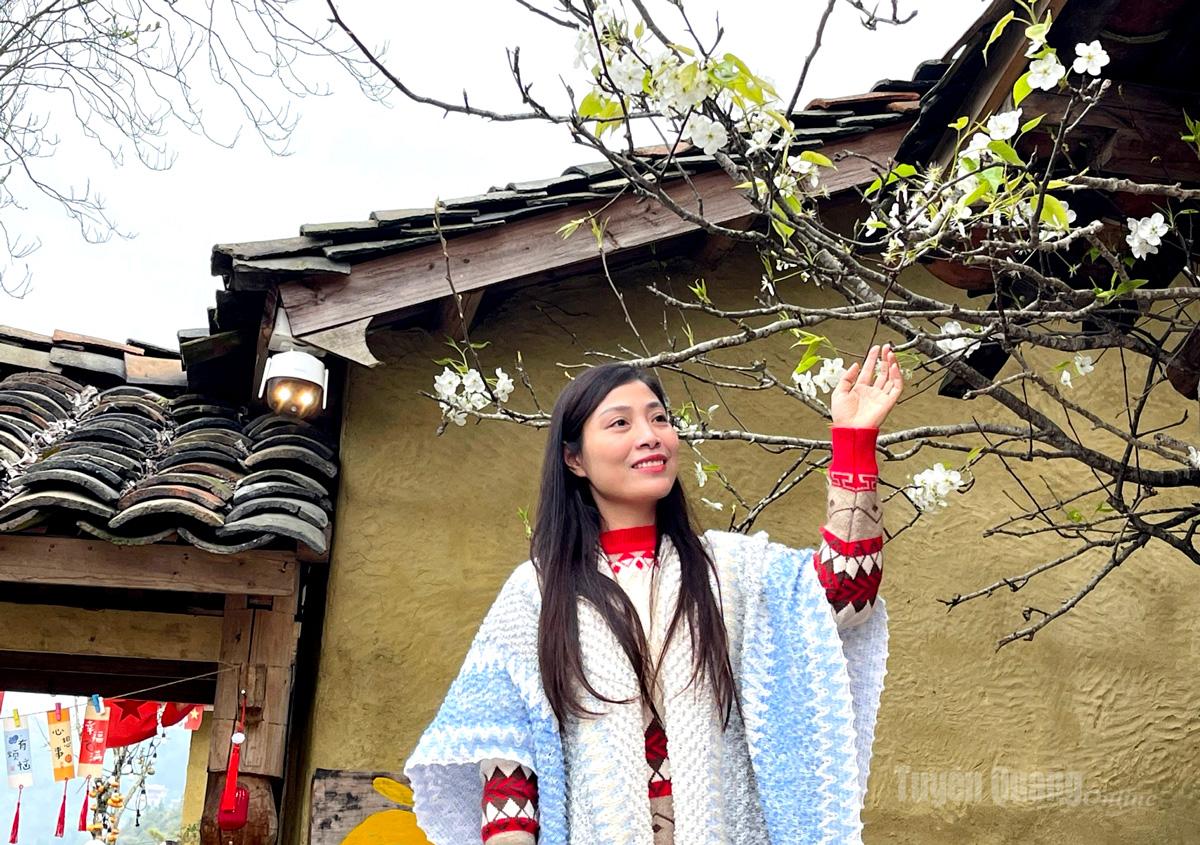 Visitors pose beside branches of white pear blossoms.