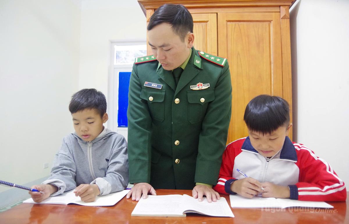Cán bộ Đồn Biên phòng Sơn Vĩ hướng dẫn các con nuôi học bài.