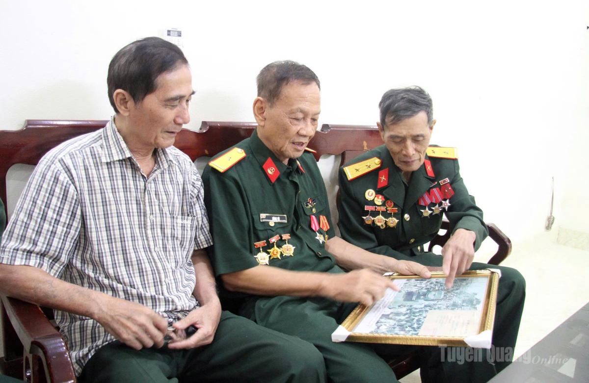 Cựu chiến binh Vũ Mộng Hùng (giữa) cùng đồng đội xem lại bức ảnh lịch sử tiến vào Dinh Độc Lập trưa 30-4-1975.