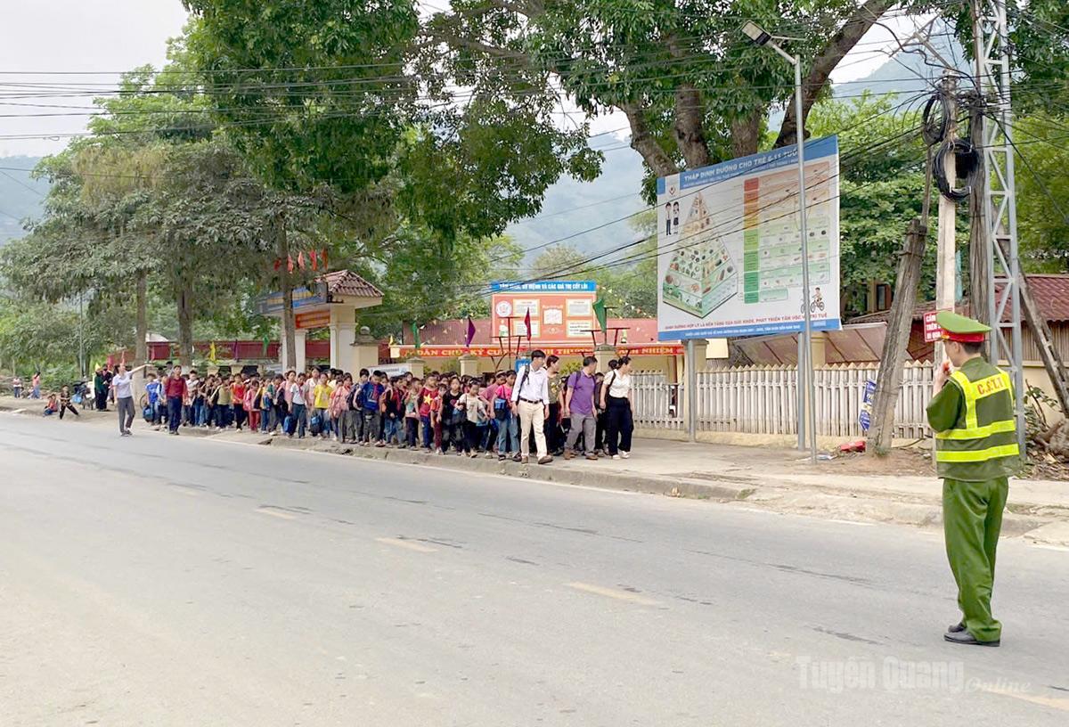 Cán bộ Công an xã Minh Tân phối hợp với giáo viên phân luồng giao thông đưa học sinh đến trường an toàn.