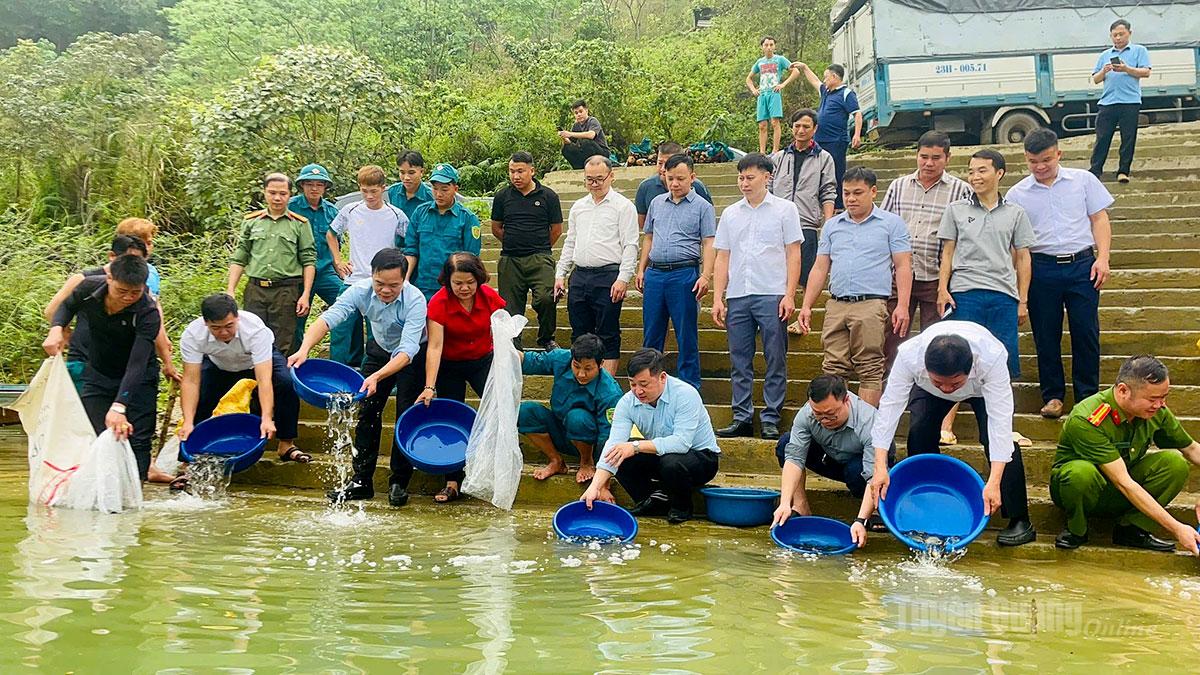 Cán bộ, công nhân viên chức và người dân xã Minh Ngọc thả cá giống xuống lòng hồ thủy điện Na Hang.