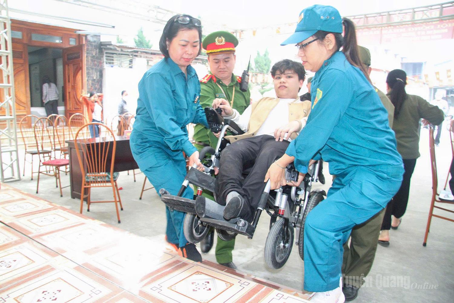 Lực lượng chức năng hỗ trợ người khuyết tật tham gia bỏ phiếu tại khu vực bỏ phiếu số 33, Nhà văn hóa tổ 9, 10, phường Minh Xuân.
