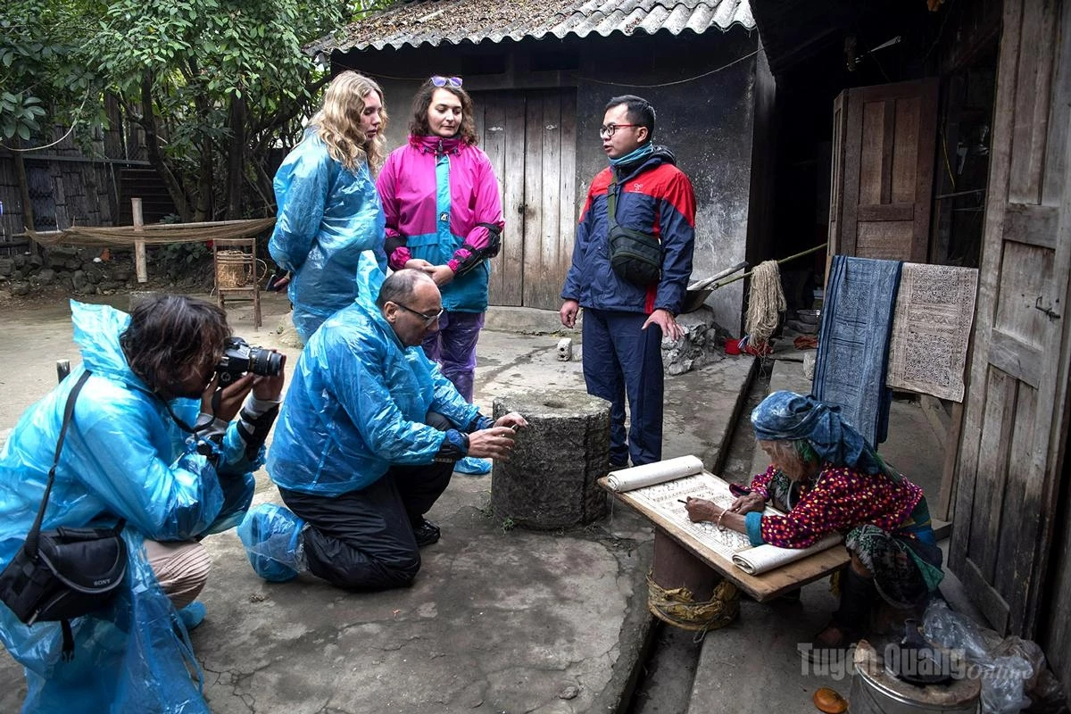 Foreign tourists experience and learn about the Mong people’s beeswax painting art.