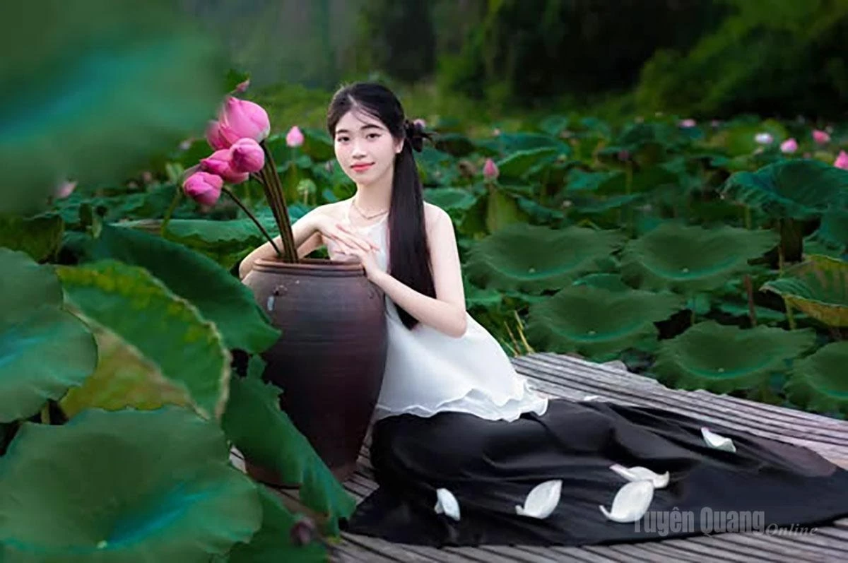 A graceful young woman poses beside the Hai Thao lotus pond in Nong Tien Ward.