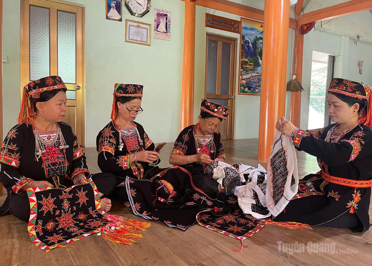 Các bà, các cô trong thôn nhận thêu trang phục cho chị Lý.