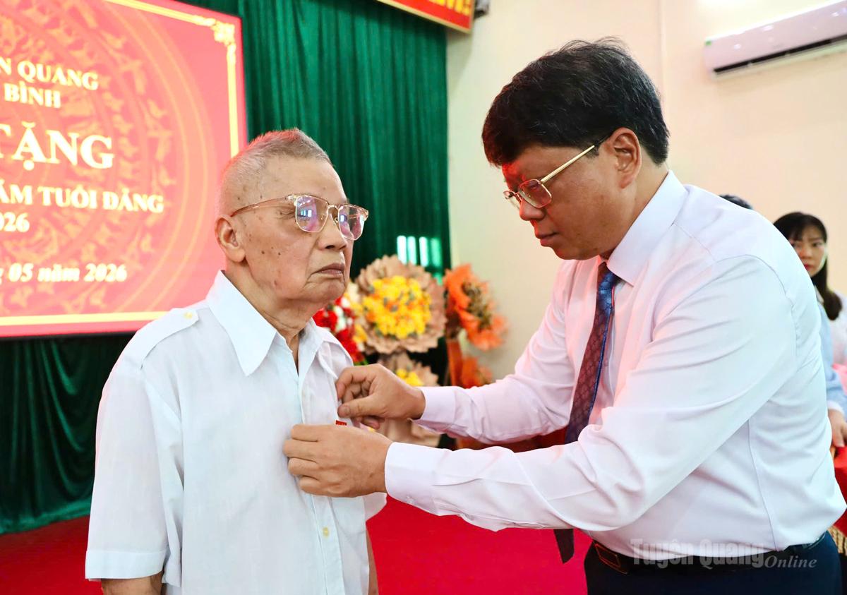 Đồng chí Hà Trung Kiên, Ủy viên Ban Thường vụ Tỉnh ủy, Phó Chủ tịch Thường trực Ủy ban MTTQ tỉnh gắn Huy hiệu 65 năm tuổi Đảng cho đảng viên Nông Văn Tiêu, Chi bộ thôn Kim Quang, xã Kim Bình.