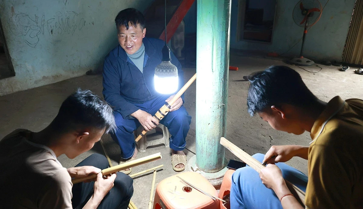 To ensure the sound of the Hmong flute continues to resonate for future generations, training young successors has become a key priority for the local community. In the photo, village head Mua Mi Lu is guiding two young villagers through the steps involved in crafting a Hmong flute.