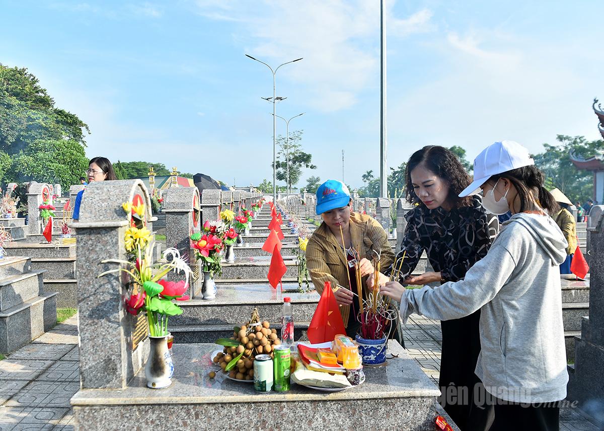 Đồng chí Phó Tổng Biên tập Báo và phát thanh, truyền hình Tuyên Quang Ngô Thị Thu Hà và thân nhân liệt sĩ thắp hương mộ liệt sĩ.