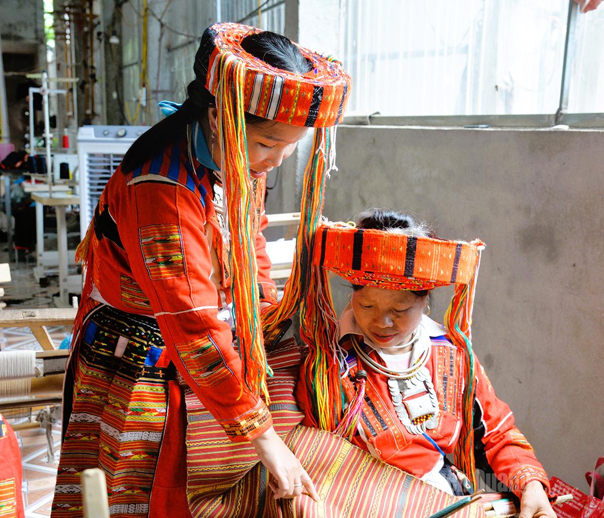 Ms. Tai Thi Mai (left), Director of Pa Then Tan Bac Brocade Cooperative, inspects brocade weaving products.