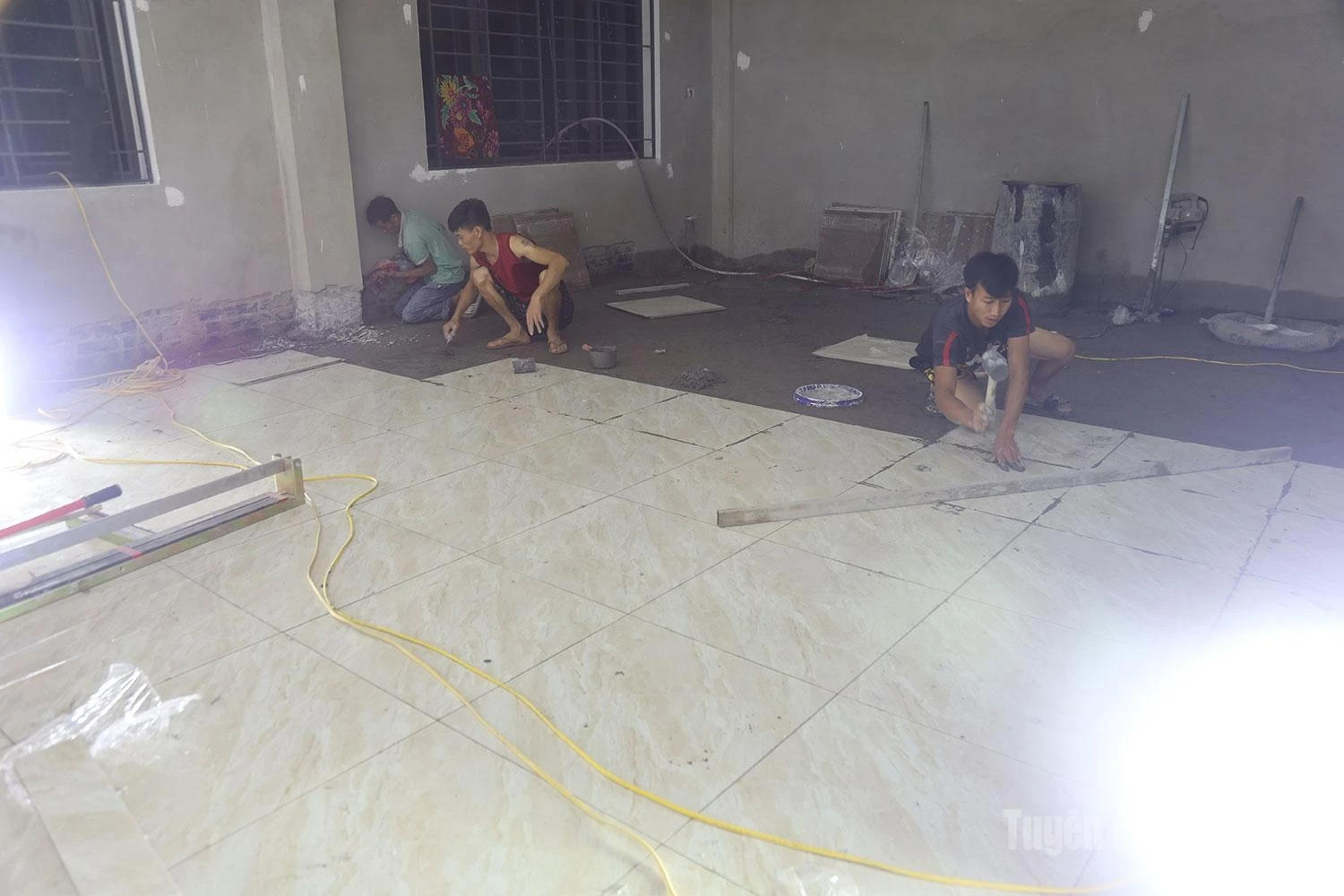 Under the bright construction lights, workers are racing against time to lay floor tiles in the classrooms.