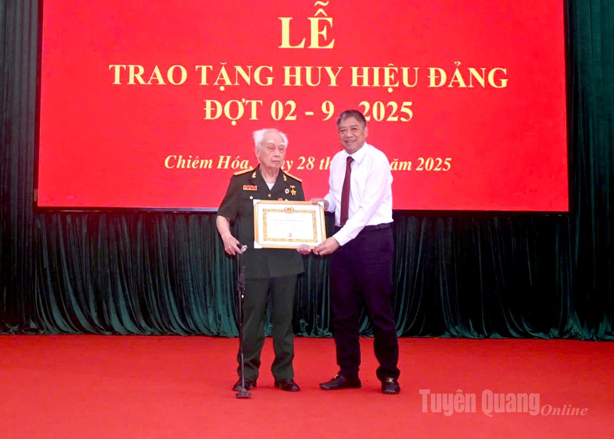 Đồng chí Nguyễn Hồng Trang trao Huy hiệu 70 năm tuổi Đảng cho đảng viên Mã Tân Văn, Chi bộ thôn Vĩnh Thịnh, Đảng bộ xã Chiêm Hóa.
