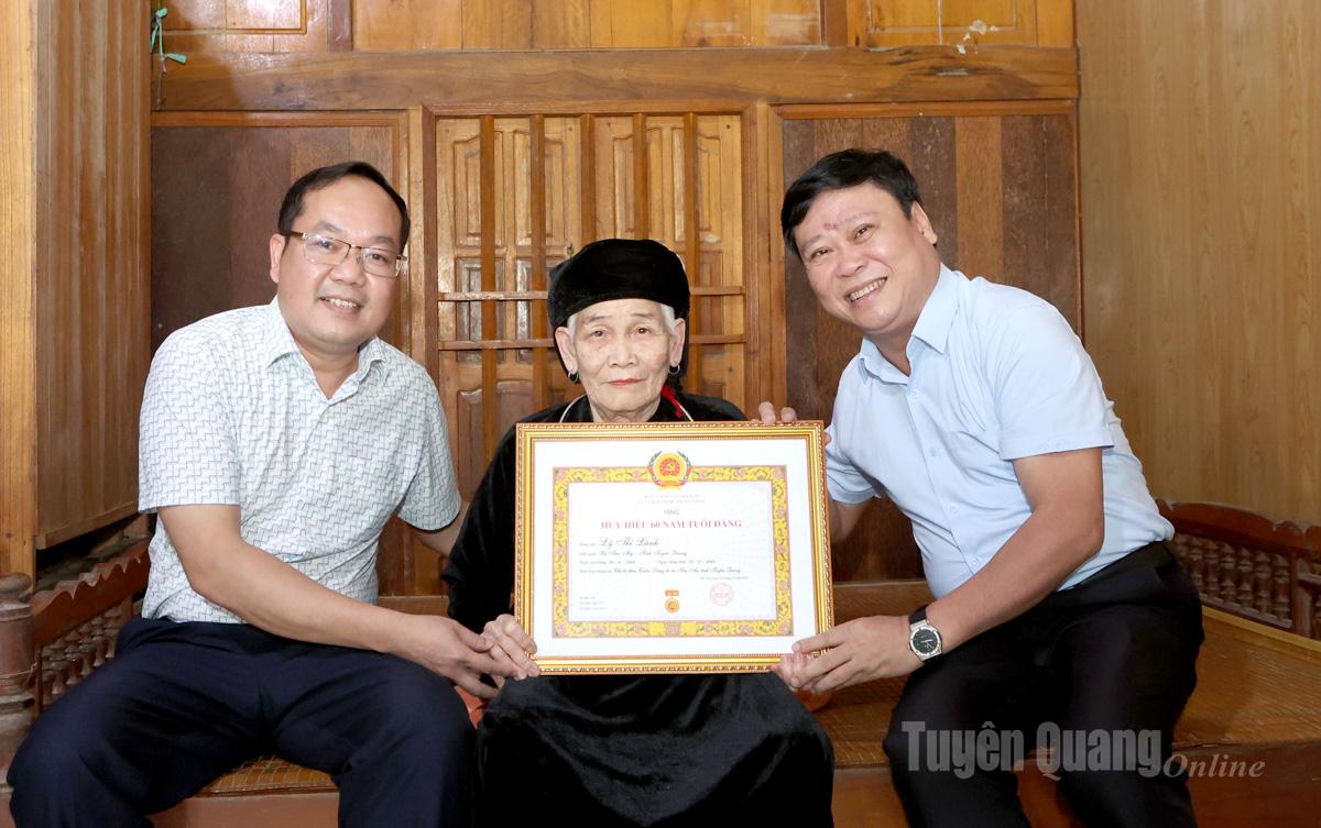 Đồng chí Mai Đức Thông, Ủy viên Ban Chấp hành Đảng bộ tỉnh, Tổng Biên tập Báo và phát thanh, truyền hình Tuyên Quang, Chủ tịch Hội Nhà báo tỉnh (ngoài cùng bên phải) trao tặng huy hiệu 60 năm tuổi Đảng cho Đảng viên Lý Thị Lành, chi bộ thôn Cuôn.