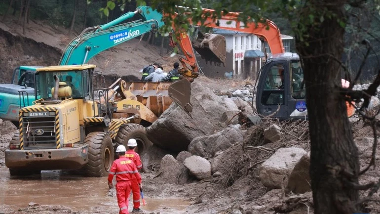 Lực lượng chức năng đang sửa chữa đoạn đường bị lũ quét tàn phá. (Ảnh: Tân Hoa Xã)