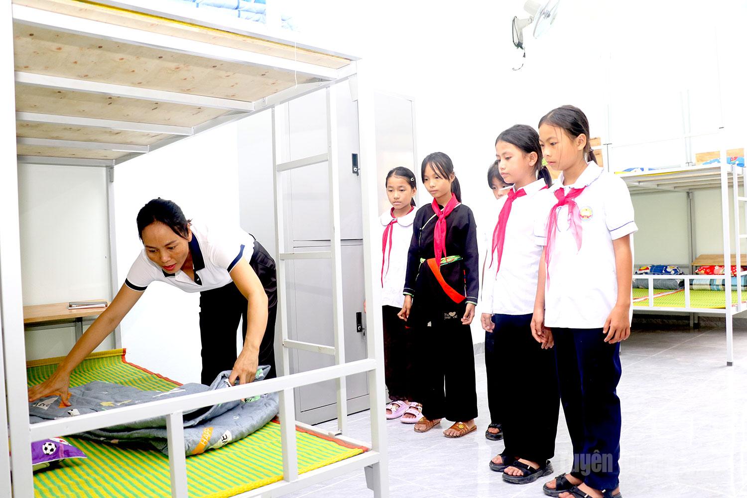 Cô giáo tận tình hướng dẫn học sinh gấp chăn, sắp xếp đồ dùng – những việc nhỏ giúp các em từng bước tự lập và trưởng thành.