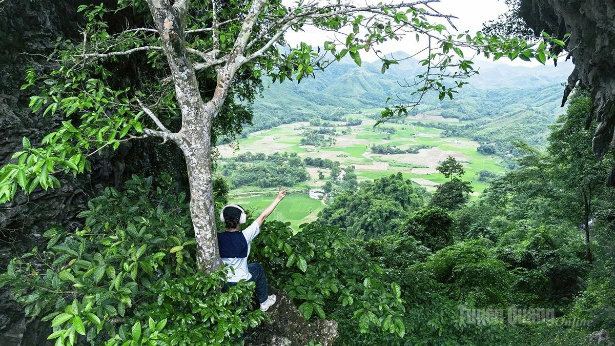 The perforated mountain resembles an immense natural archway, offering a sweeping view of the lush, tranquil village below.