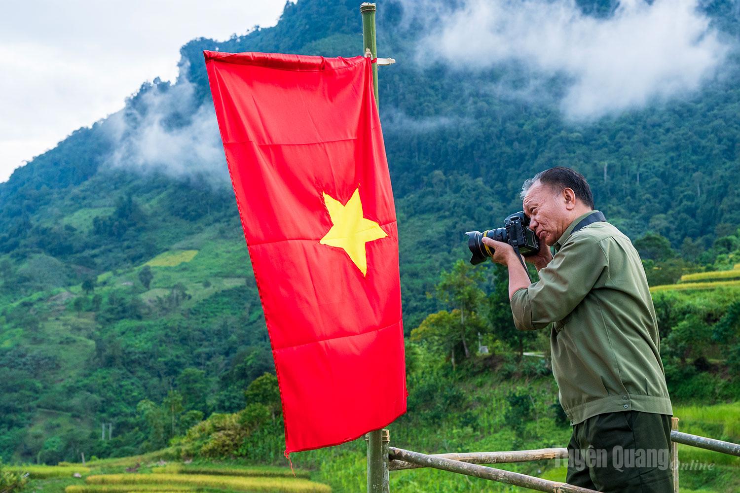 Nghệ sĩ nhiếp ảnh sáng tác với cờ Tổ quốc.