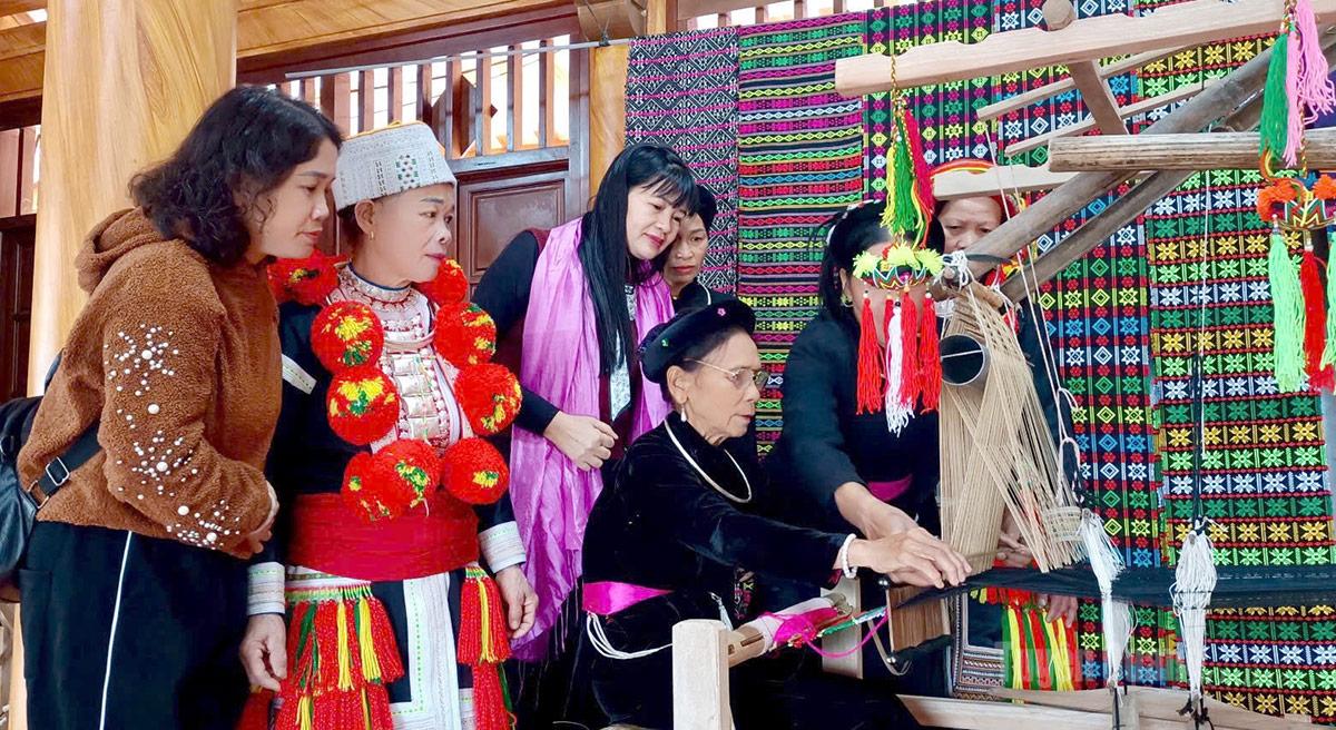 Văn hóa truyền thống bản địa là lợi thế để các làng văn hóa thu hút khách du lịch (Trong ảnh:
Khách du lịch thích thú với nghề dệt thổ cẩm truyền thống của đồng bào Tày ở Lâm Bình)