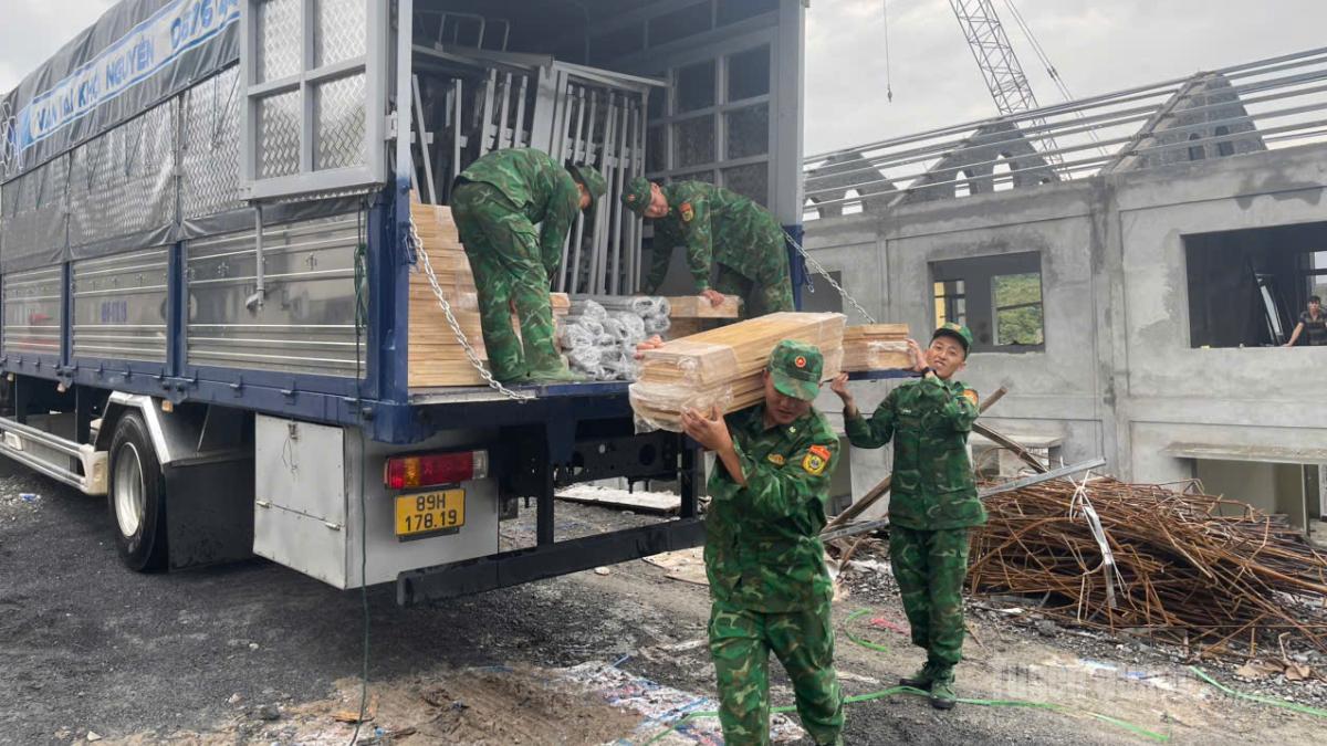 Cán bộ, chiến sĩ Đồn Biên phòng Cửa khẩu Săm Pun hỗ trợ vận chuyển vật liệu tại công trường.