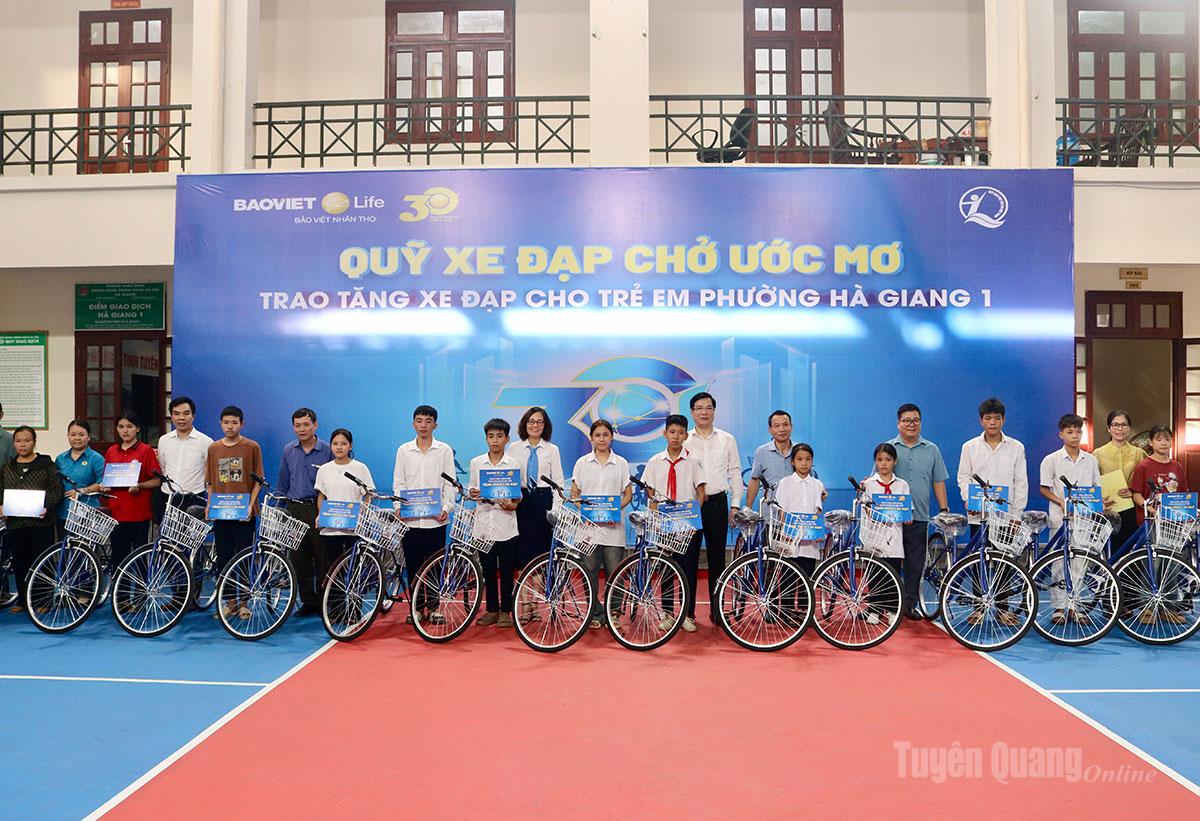 Đại diện phường Hà Giang 1 và Công ty Bảo Việt Nhân thọ Hà Giang trao xe đạp cho các em học sinh.