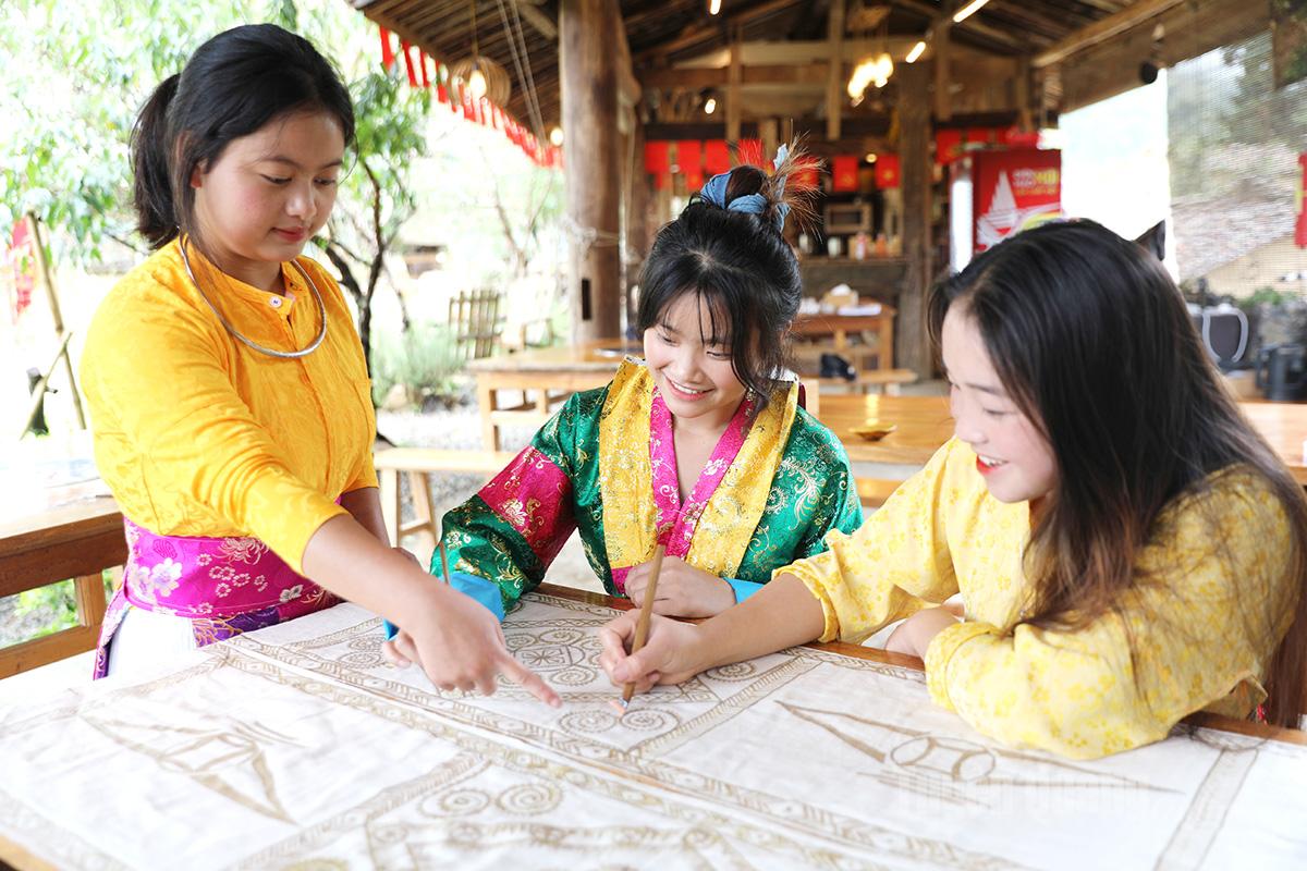 Tourists experience beeswax painting with a Mong host woman.