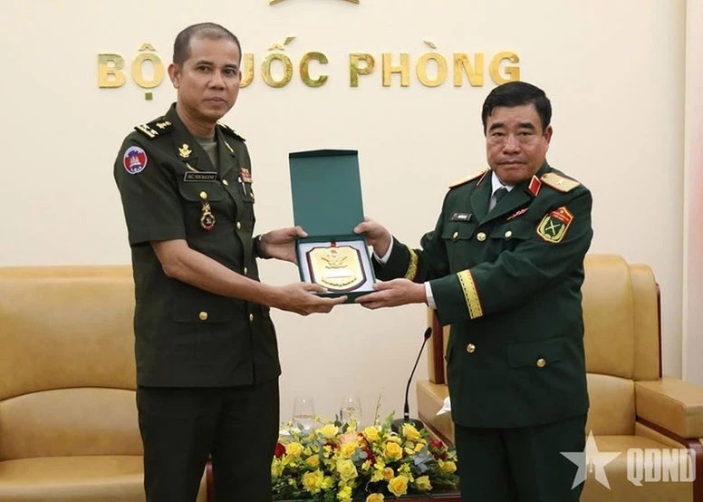 Major General Nguyen Ba Luc (R) presents a gift to Lieutenant General Nim Balene. (Photo: qdnd.vn)