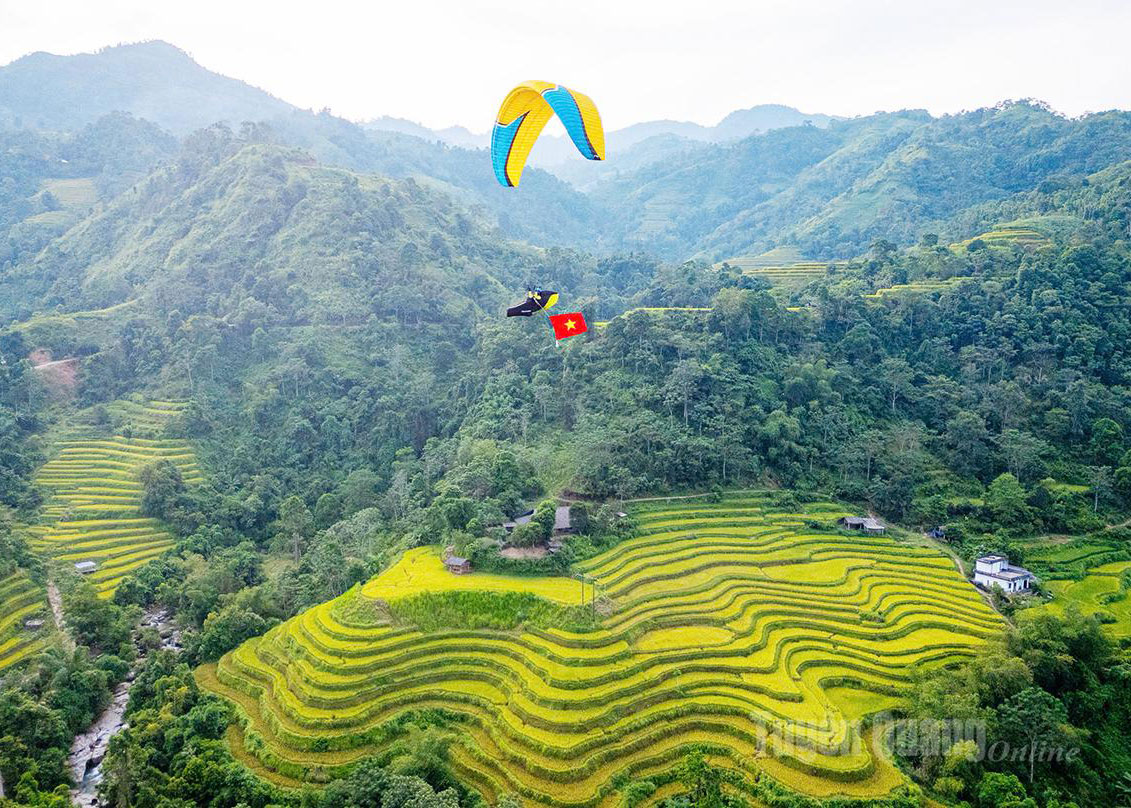 Tourists explore the terraced fields in Thong Nguyen commune by paragliding.

