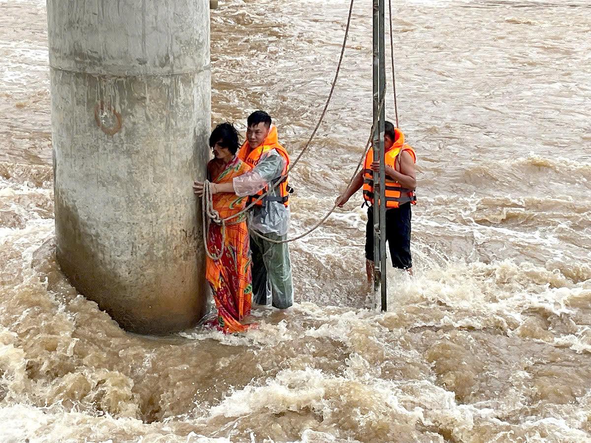 Lực lượng Quân sự và Công an xã Tùng Bá cứu hộ công dân bị mắc kẹt dưới chân cầu. Ảnh: Mộc Lan